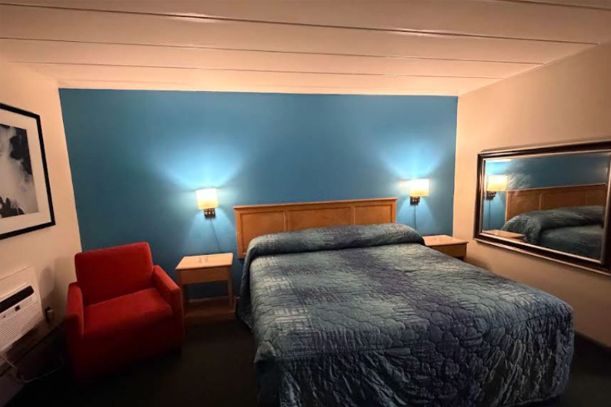 Spacious guest room with one large bed and armchair